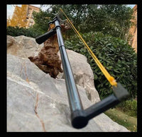 Telescopic slingshot rifle resting on a rock outdoors